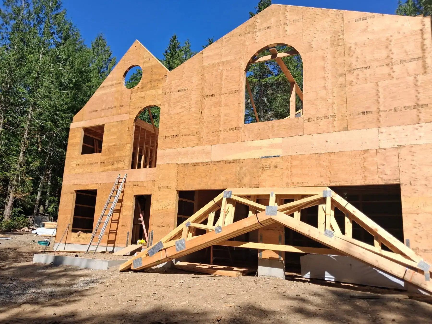 Custom home package framing with arched openings, roof structure, and timber details.