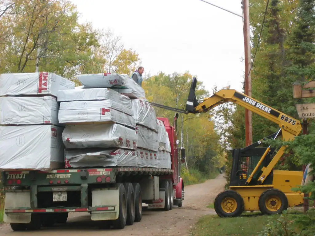 Tamlin home package being unloaded from a flatbed truck at a rural building site