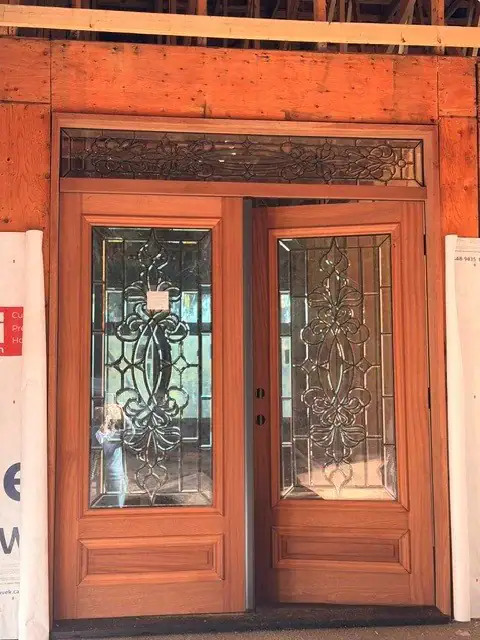 Close-up of wood double front doors with decorative glass panels and matching transom window